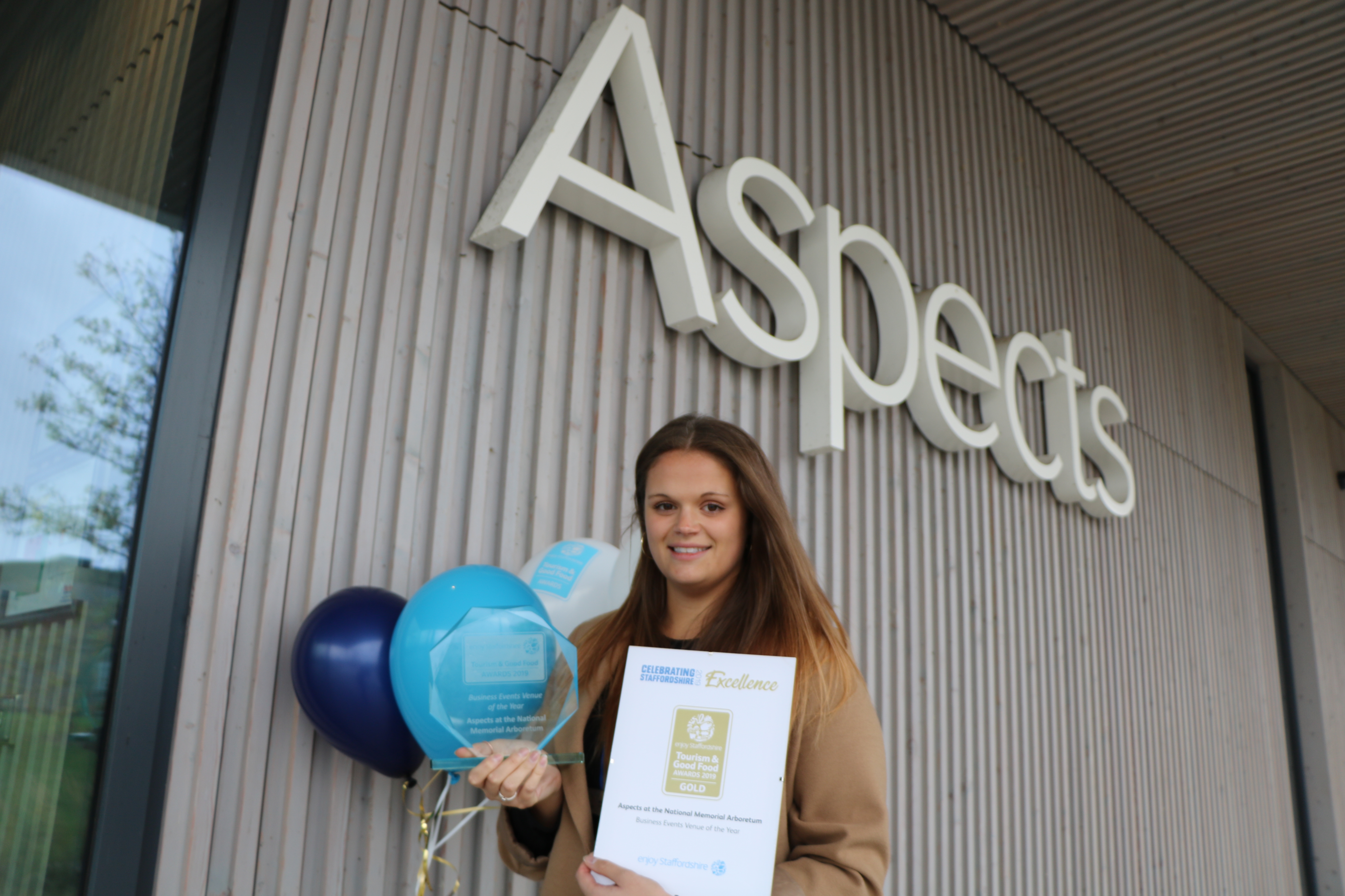 Aspects Team Member holding the Gold Award and Balloons