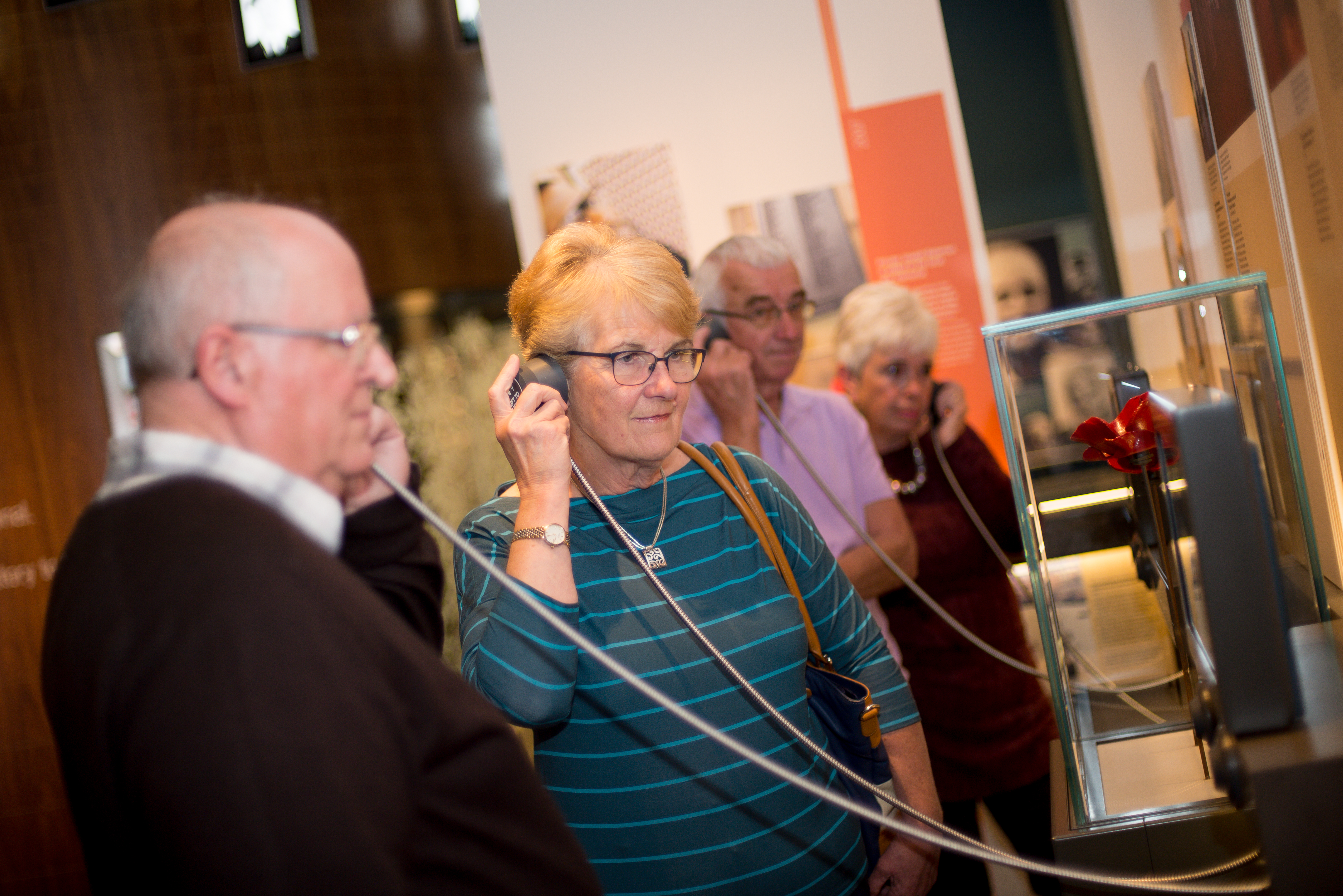 Group of visitors of a mixture of genders listening to the audio elements of the Landscapes of Lie exhibition