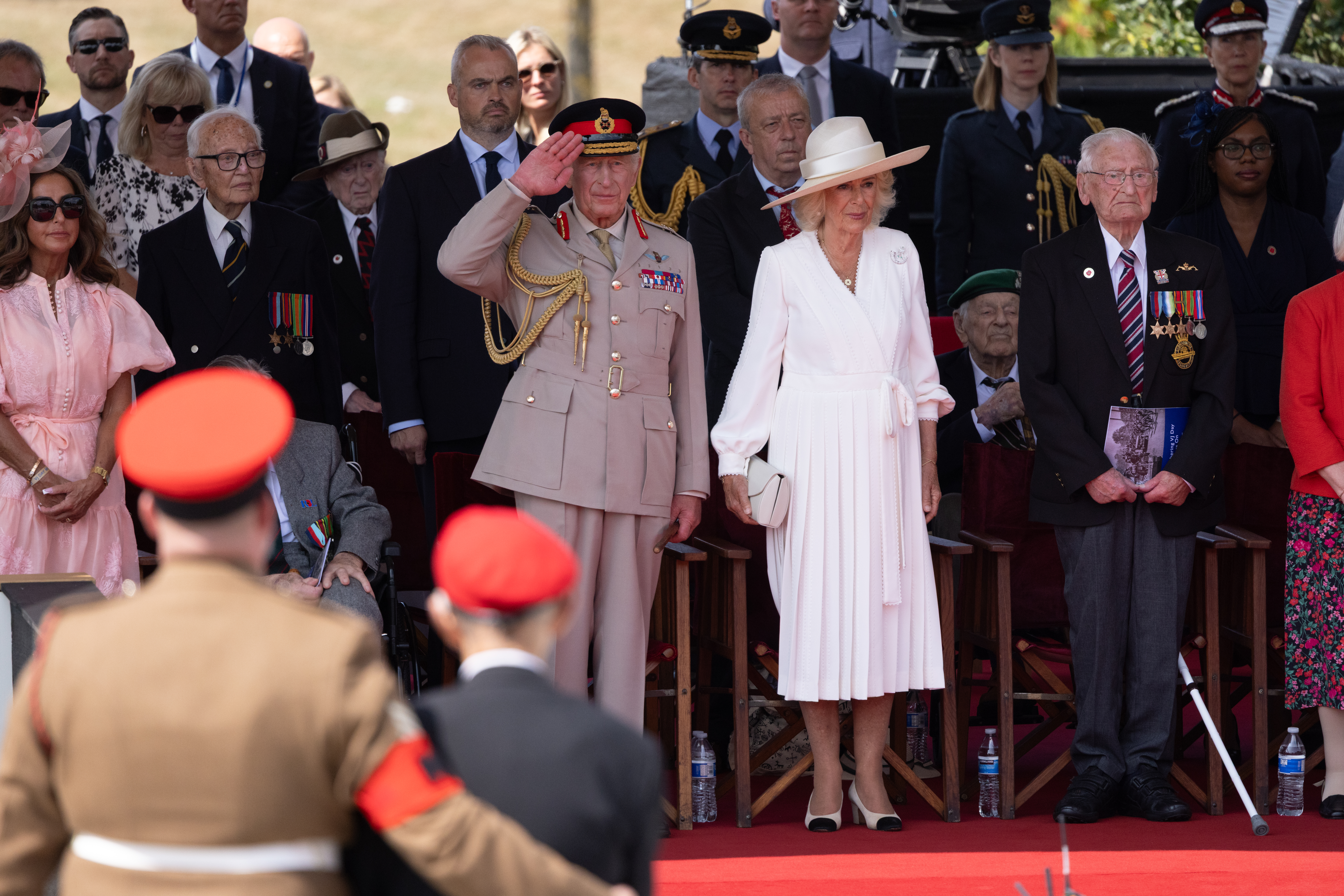 King Charles III saluting veterans alongside Queen Camilla