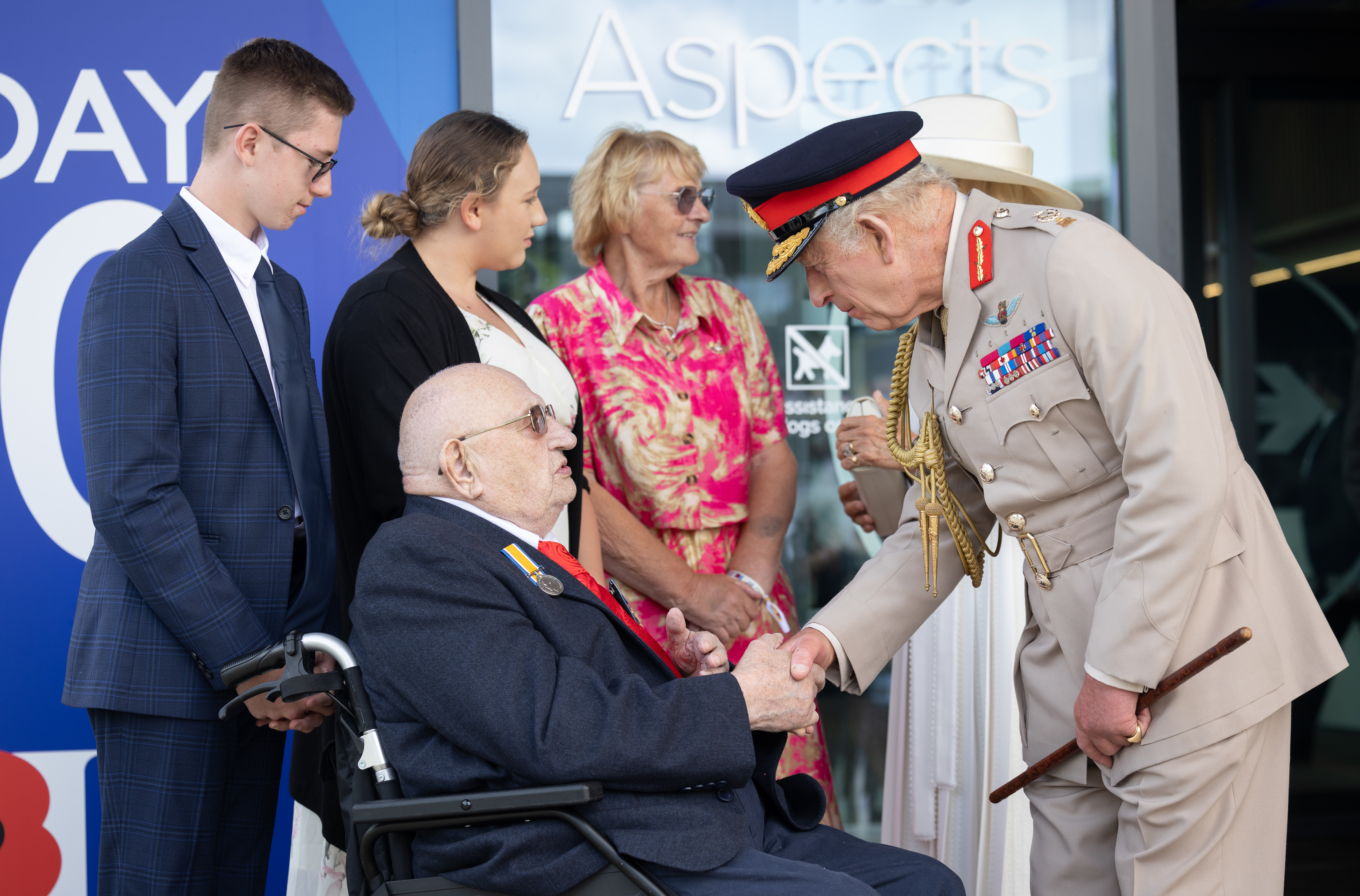 King Charles III shaking hands with a WWII veteran outside Aspects