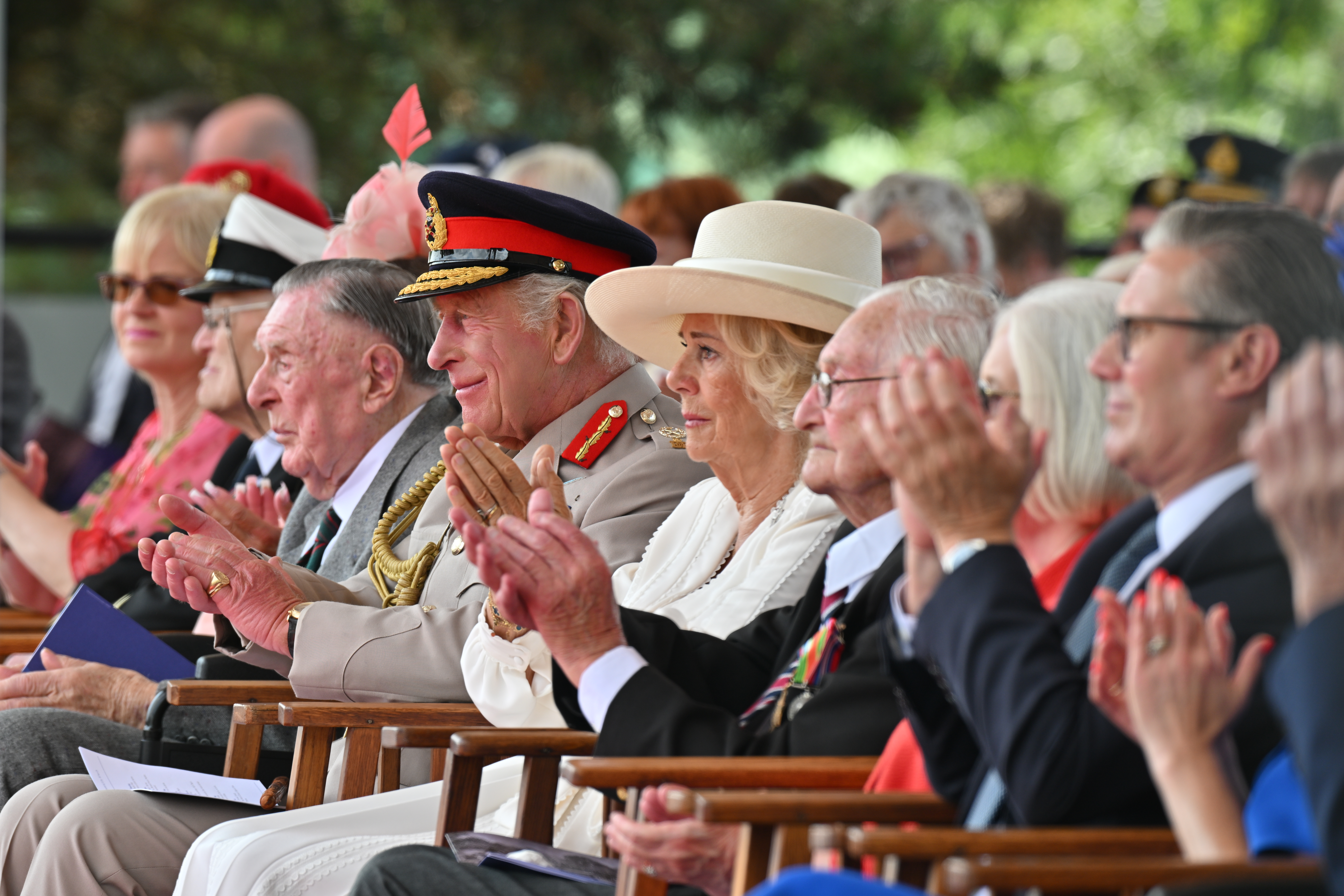 Their Majesties The King and Queen clapping alongside the Prime Minister