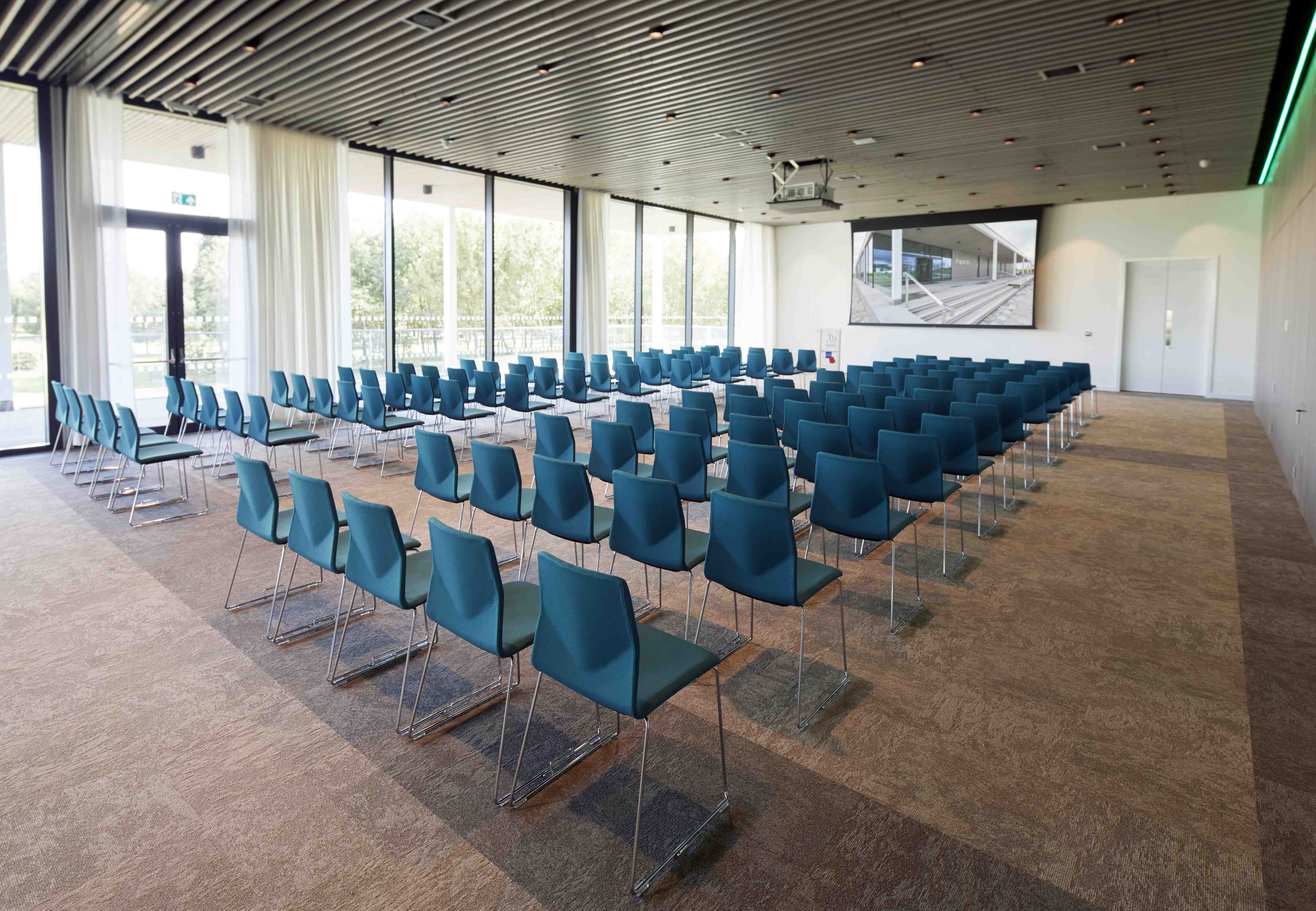 The Oak Suite in Aspects laid with rows of blue chairs all facing a screen.