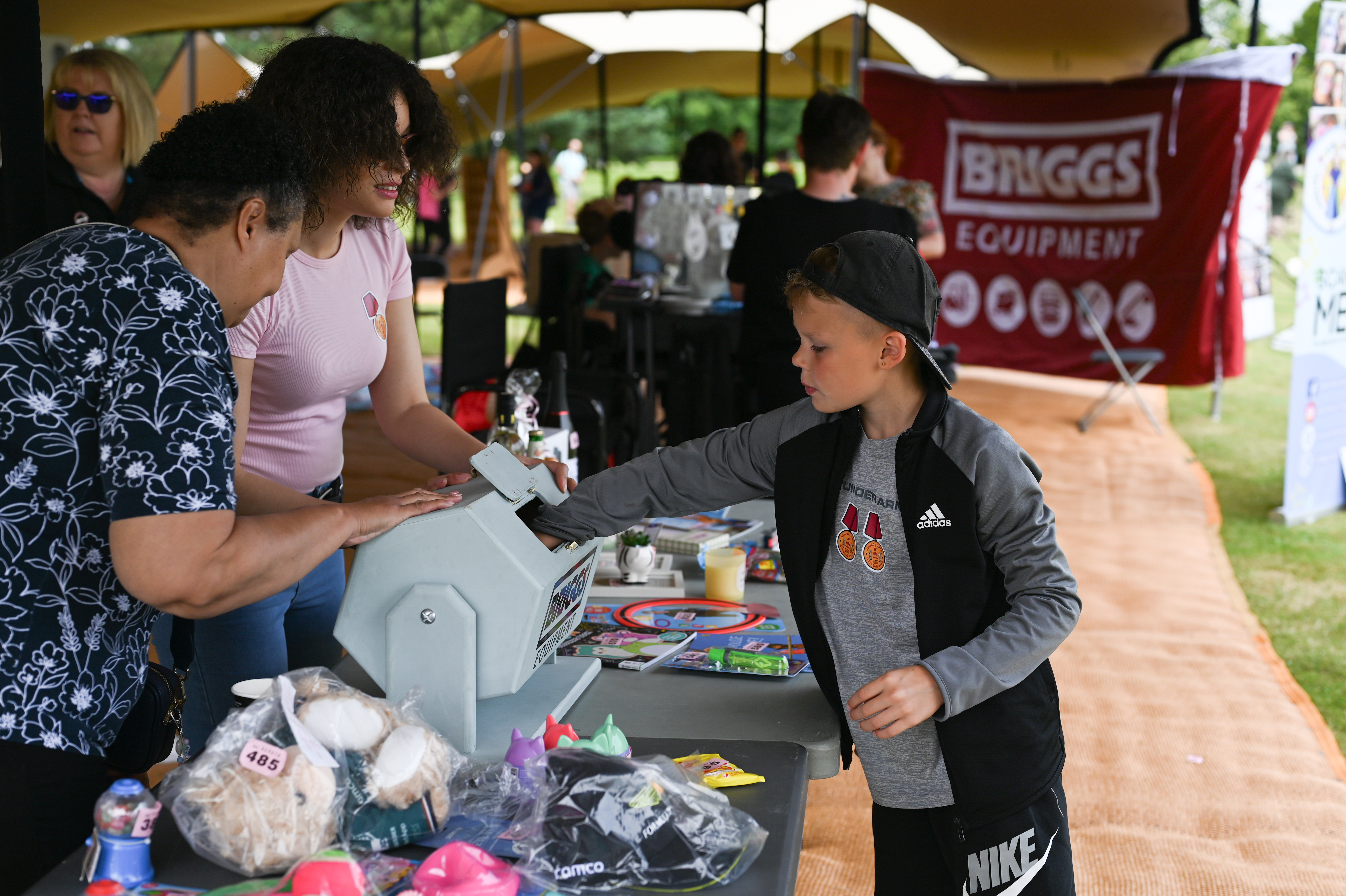 A young boy puts his hand into a tombola to pull out a ticket, at a stand run by Briggs Equipment at Armed Forces Weekend.