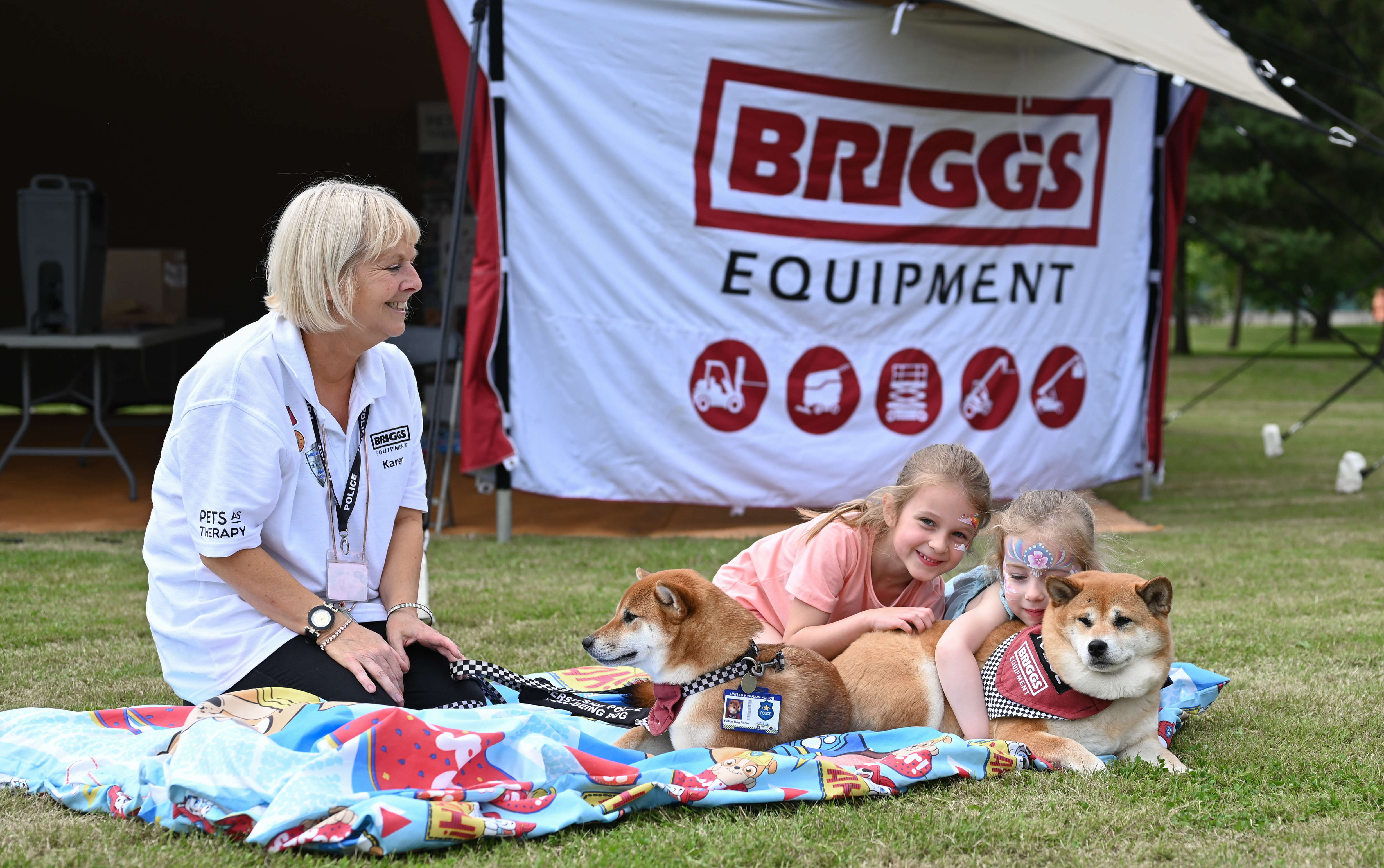 Two therapy dogs cuddle with two young girls. The dogs are wearing Briggs Equipment bandanas.
