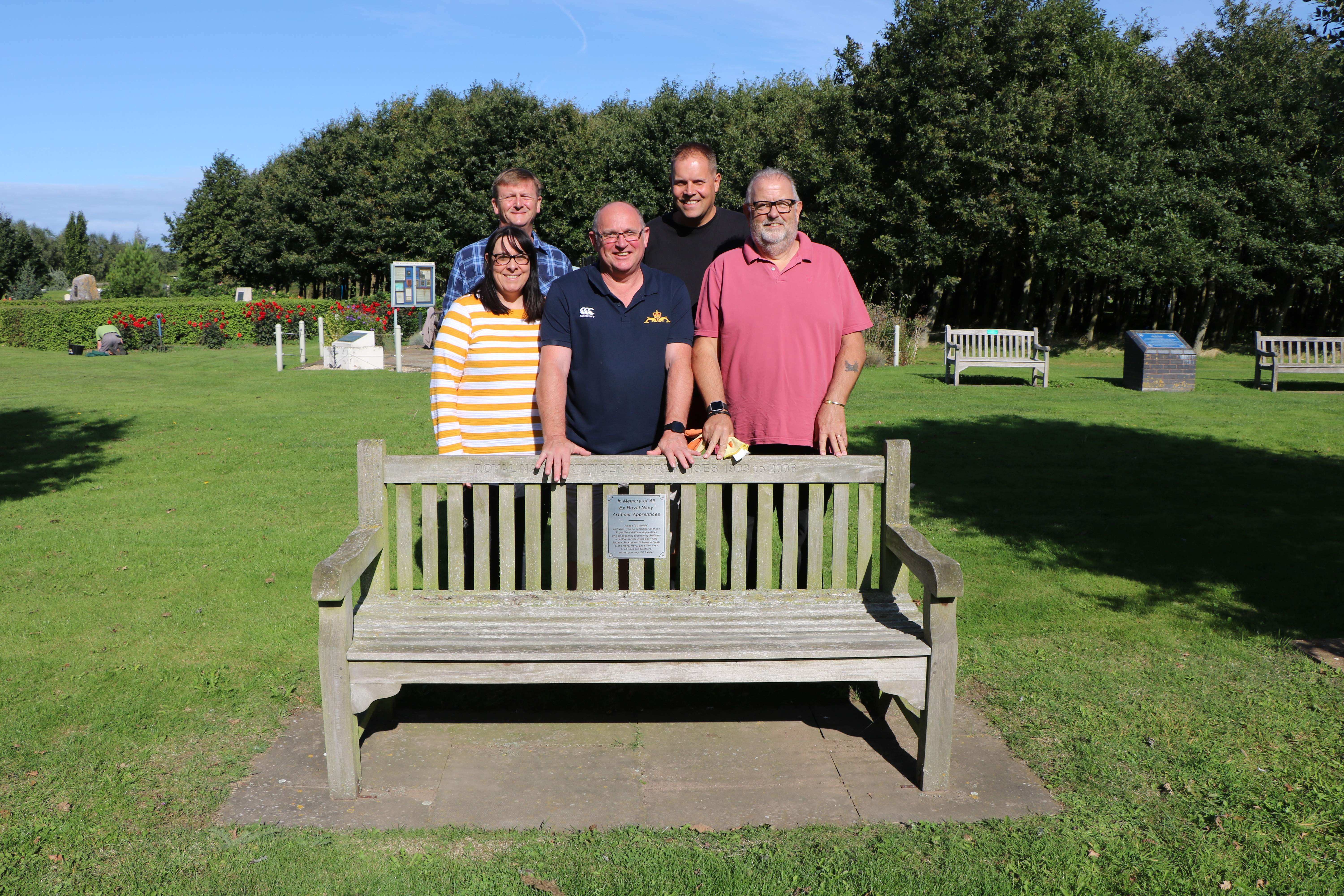Briggs Equipment employees helping to maintain the grounds at the arboretum, posing near a cleaned bench.