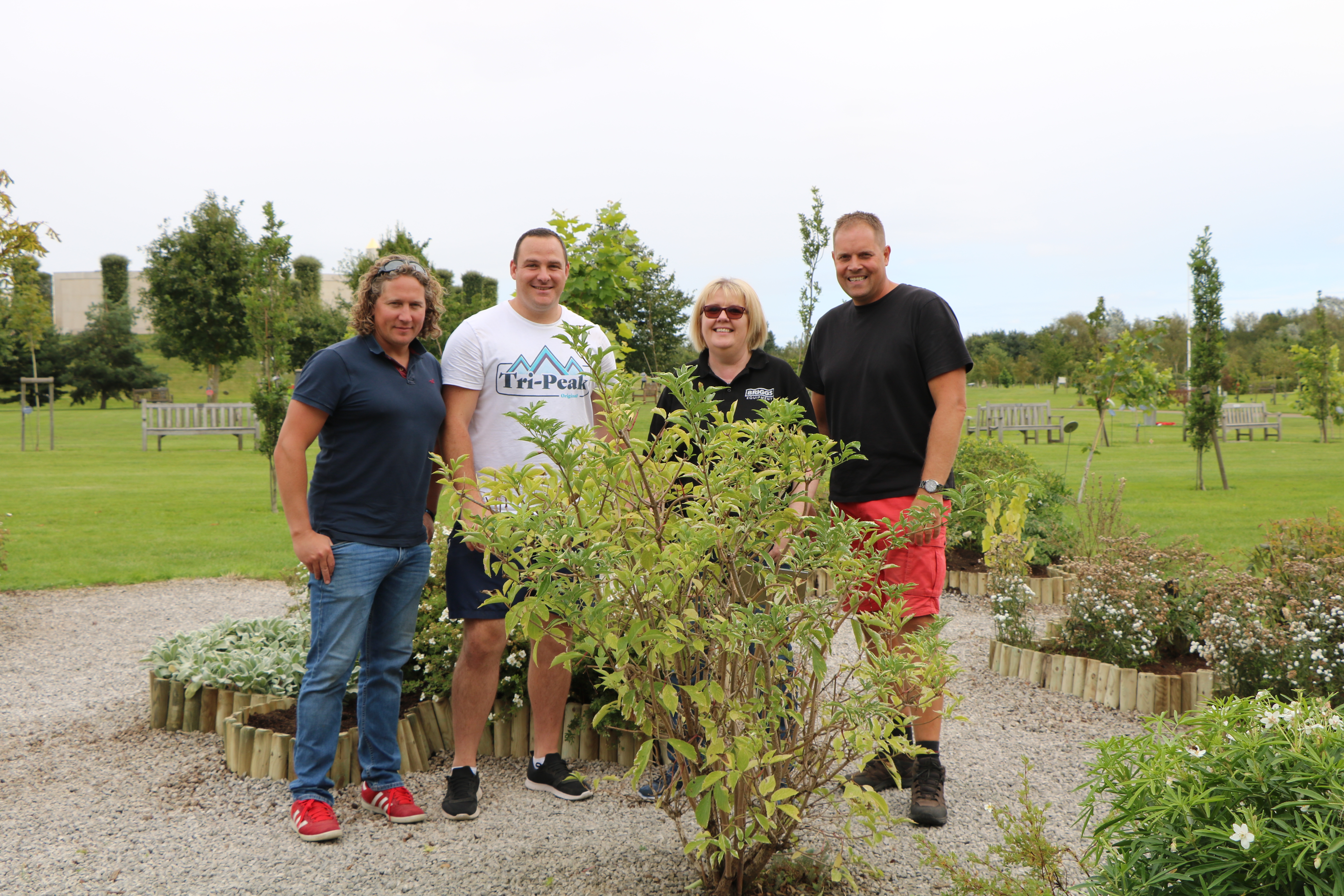 Briggs Equipment employees helping to maintain the grounds at the arboretum, posing near a pruned tree.