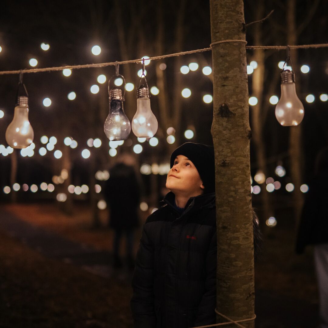 Image shows a young boy at the Illuminated event, hanging a lighted bauble as part of an interactive display.