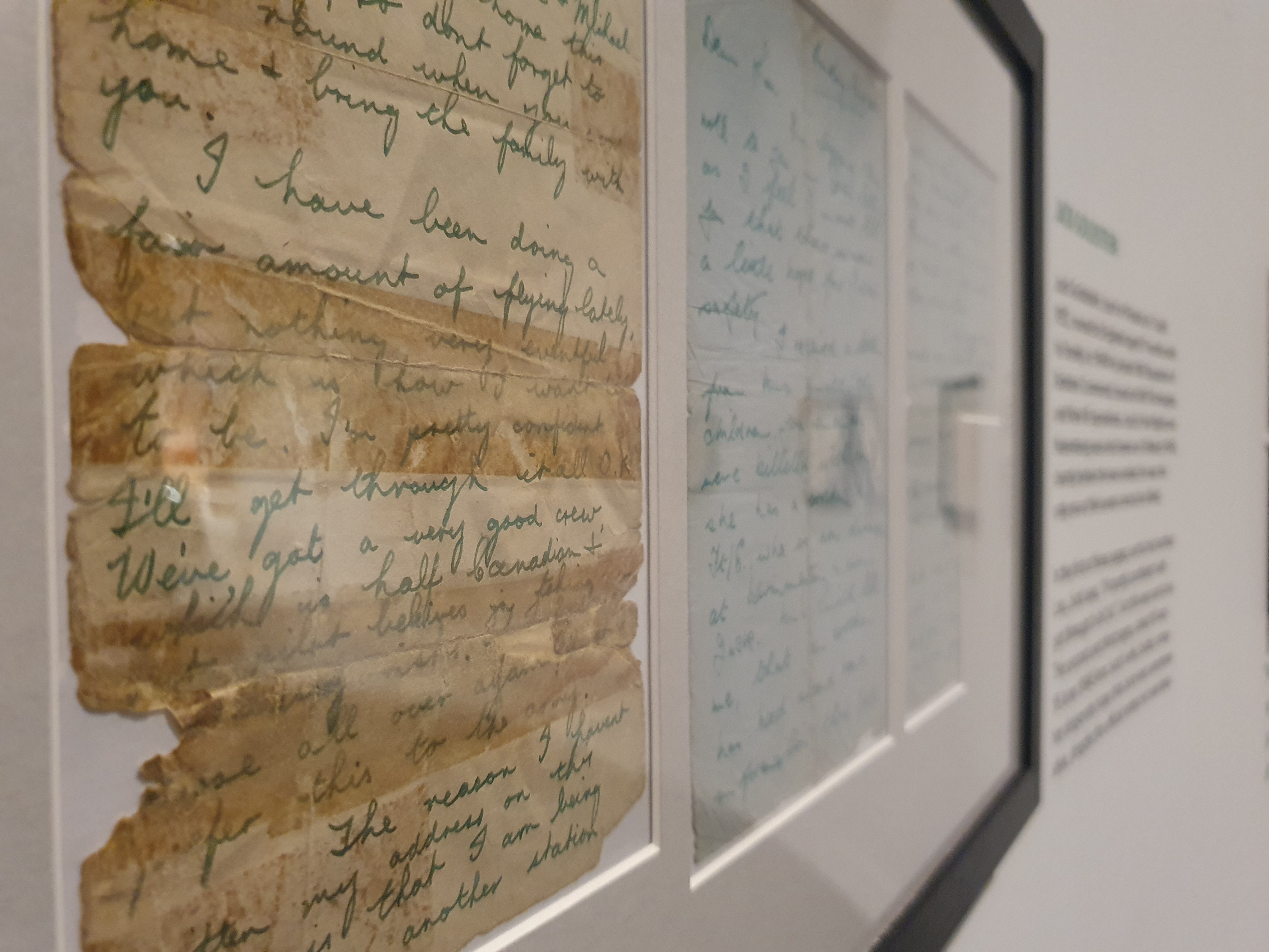 Framed letters from the Second World War, held together by tape due to their age, are displayed on a wall.