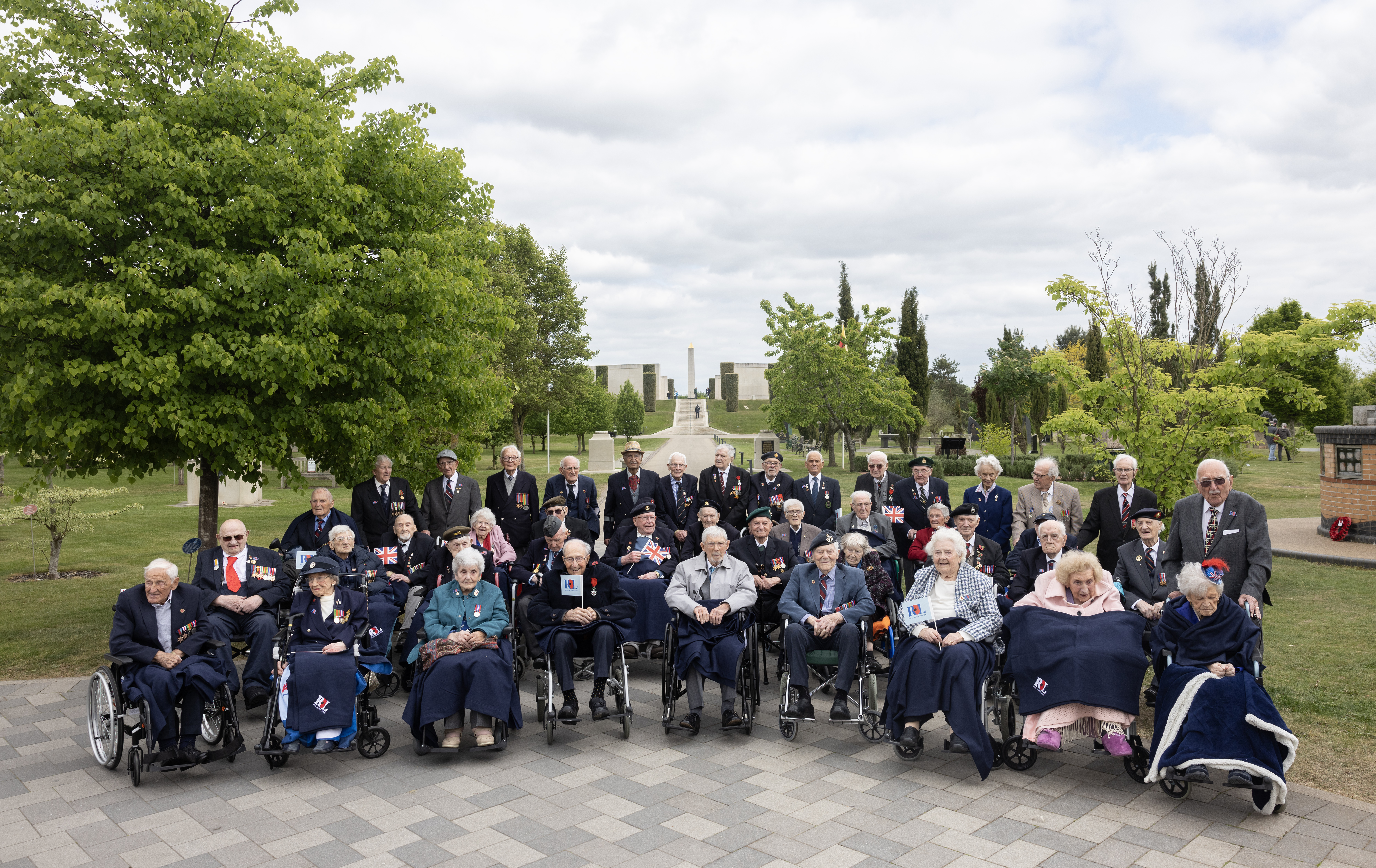A crowd of Second World War veterans stand together in front of the Armed Forces Memorial