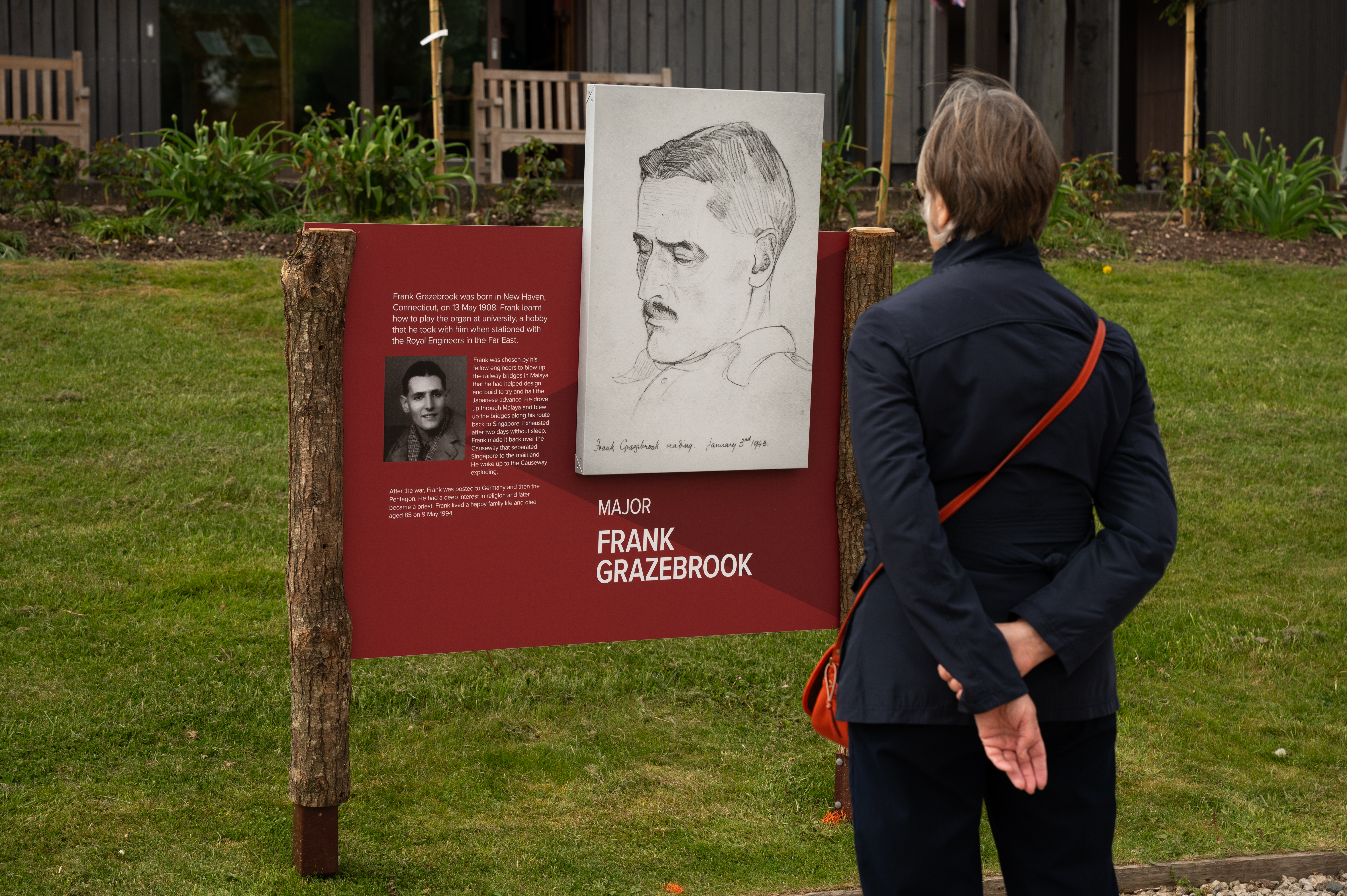 Visitor looking at the outdoor exhibition, Prisoners of War: A Chaplains Portraits, in the Amphitheatre