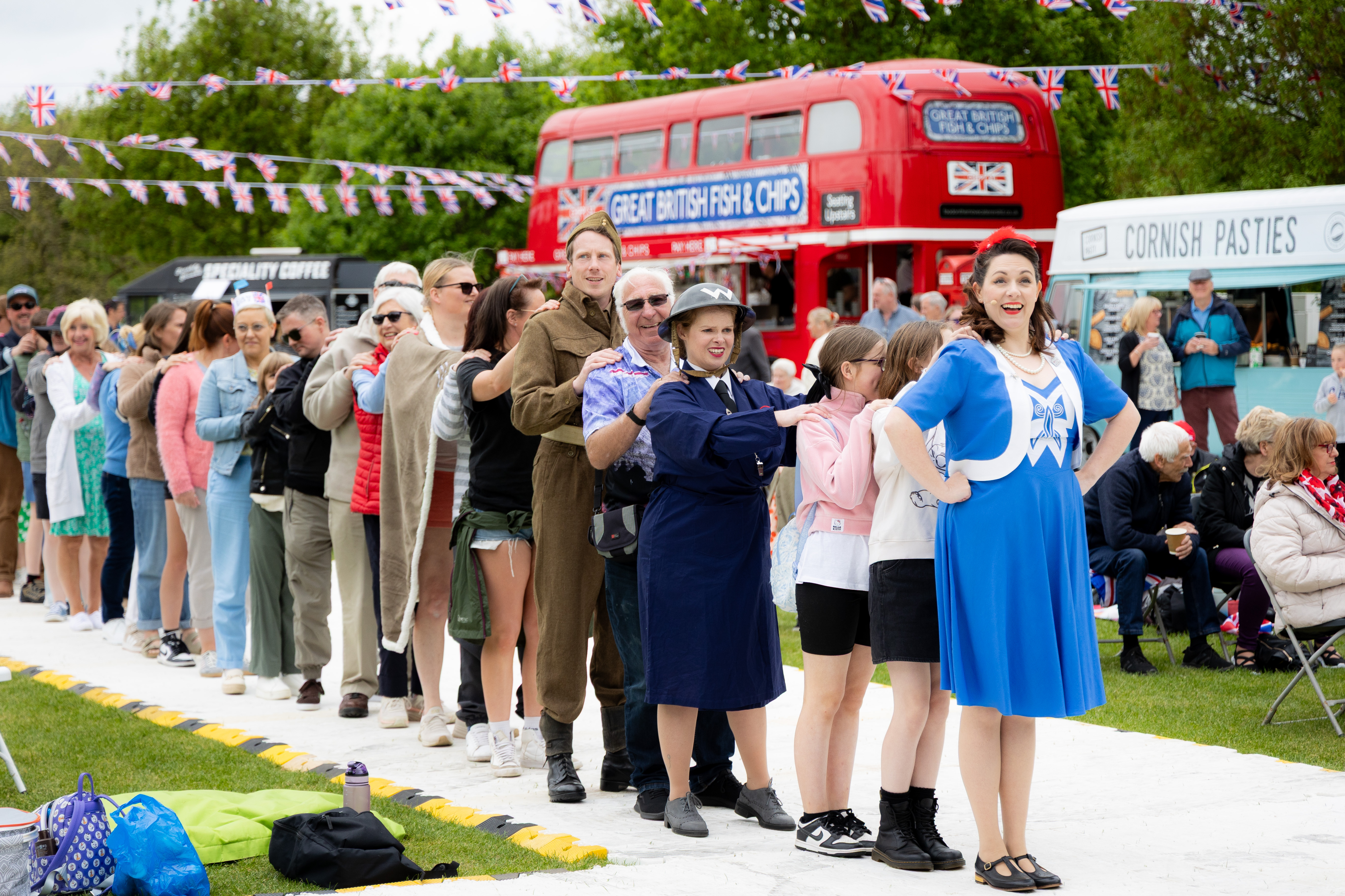 A group of Arboretum visitors form a conga line following a costumed performer