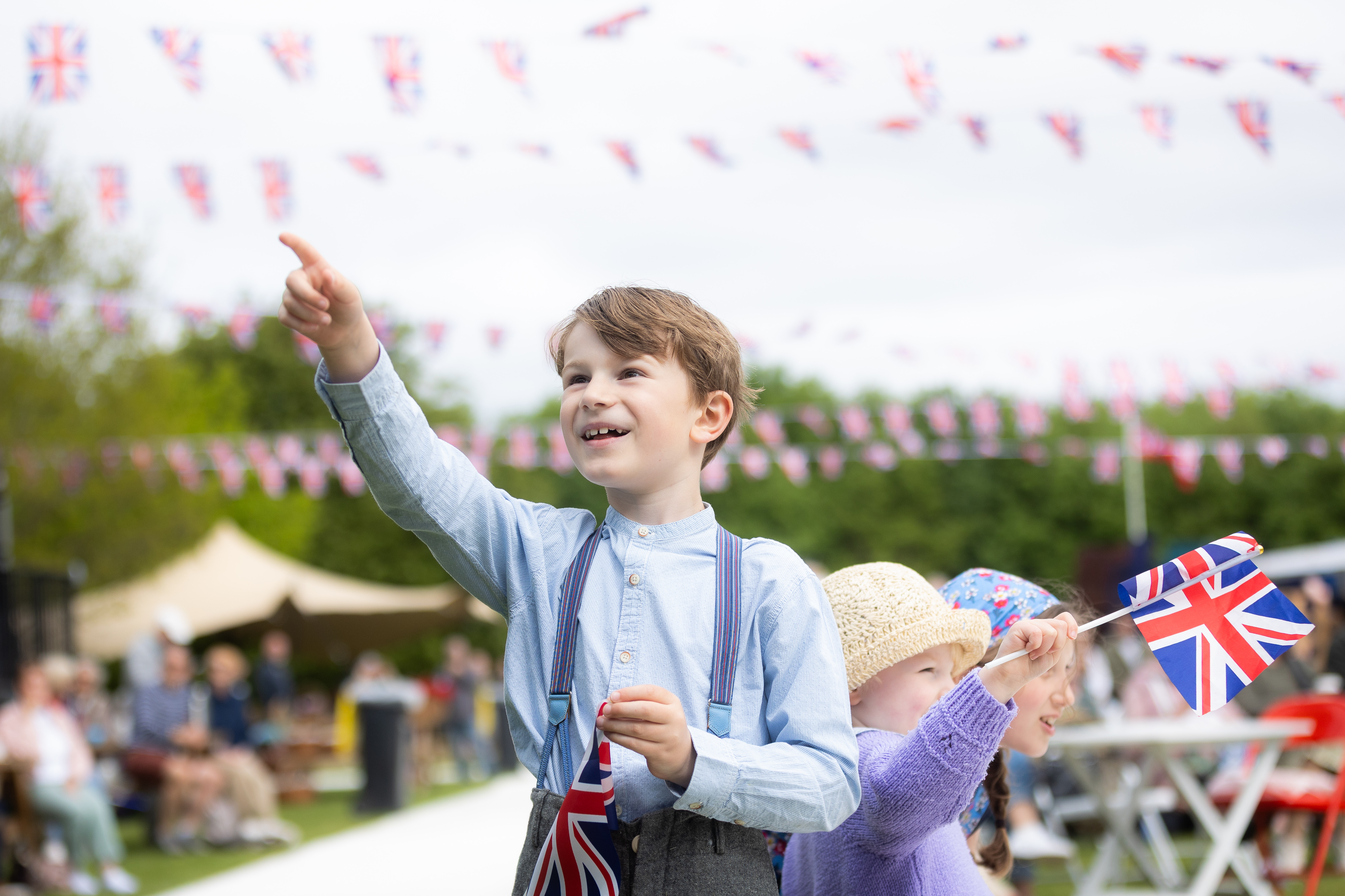 VE Day Celebrations at the Arboretum, featuring two young children in period costume waving victory flags.