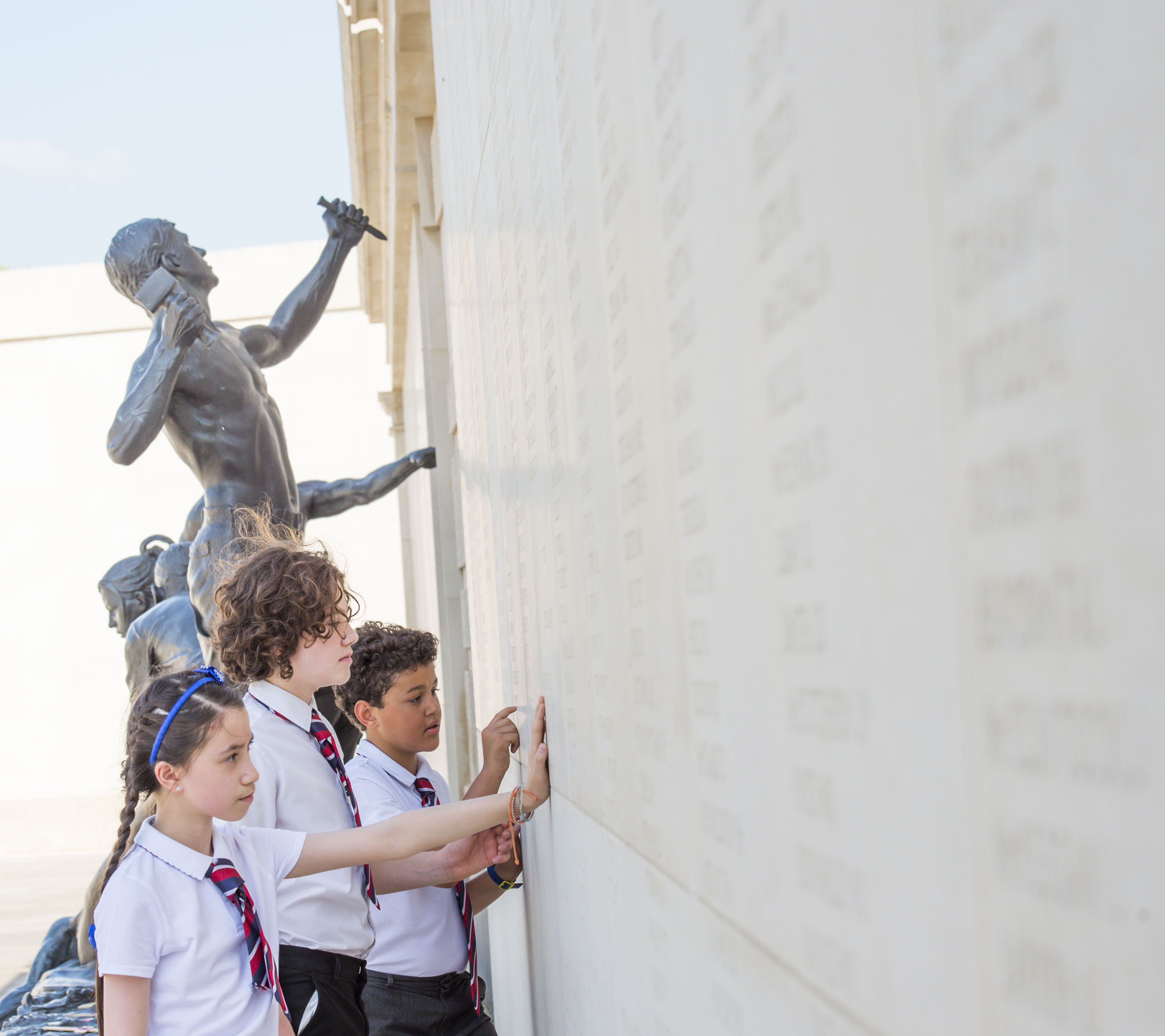 Key stage three students touch the names on the Armed Forces Memorial on a trip to the National Remembrance Gardens