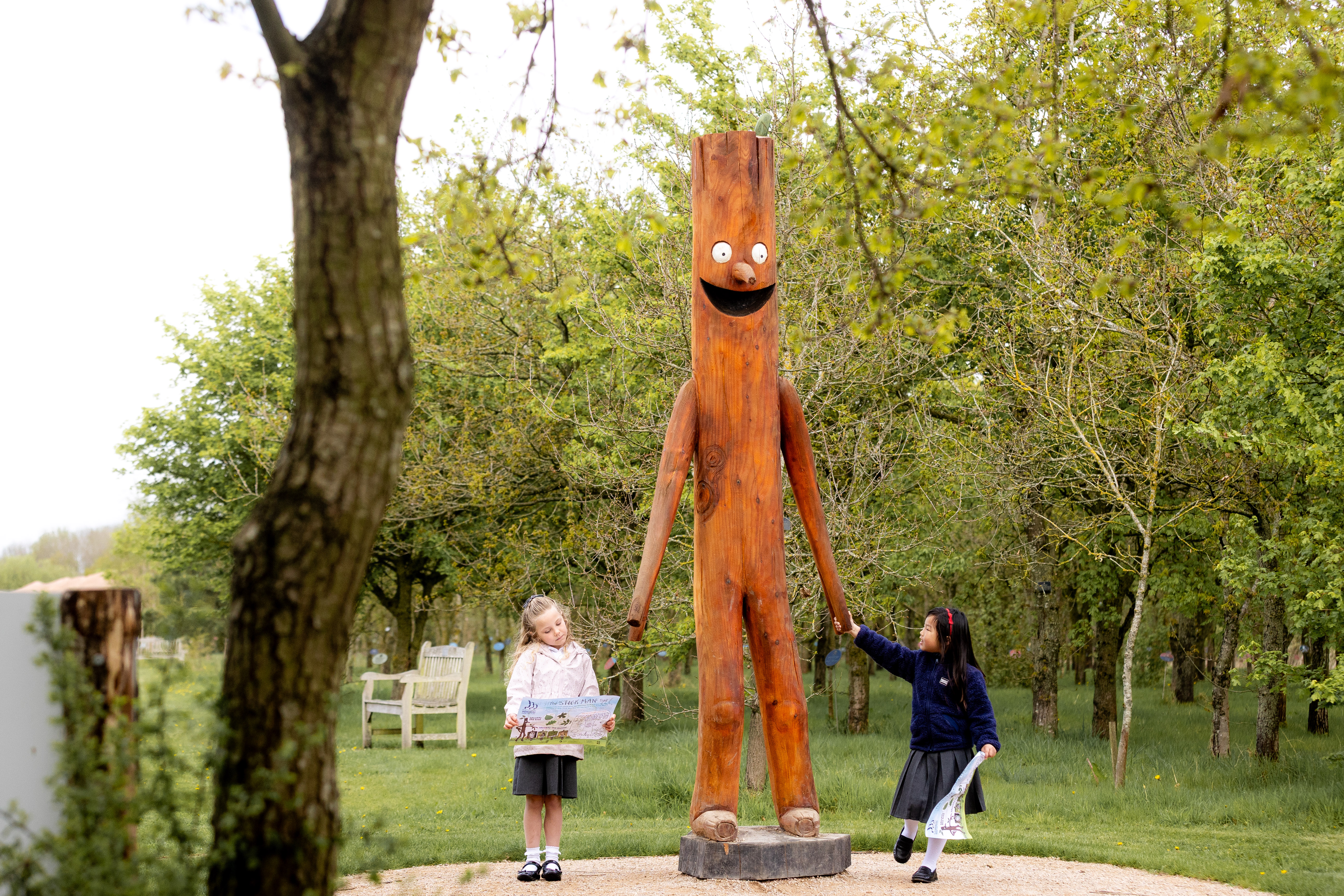 Key stage One children holding the hands of the Stick Man sculpture at the Gardens