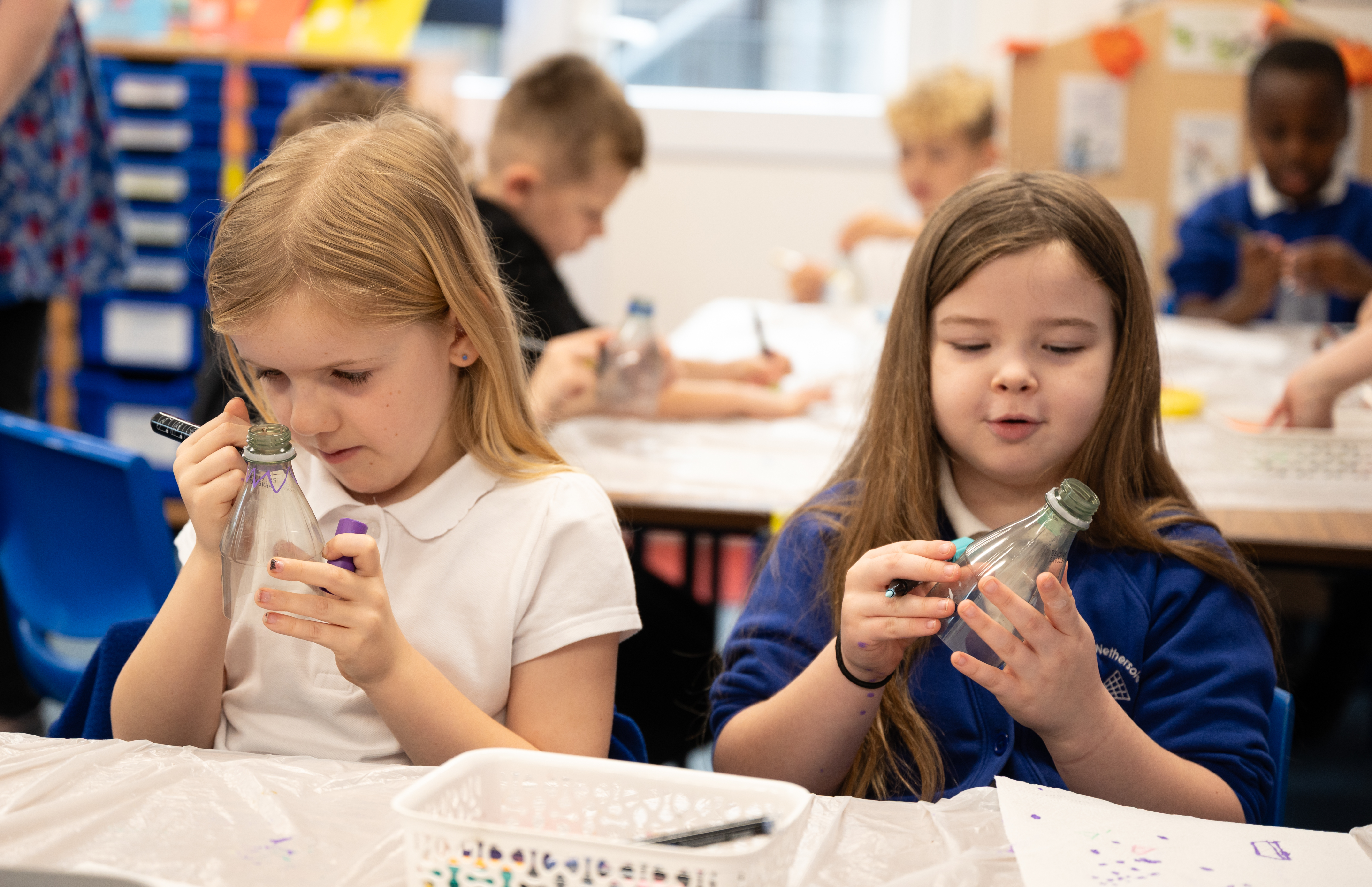 Children from a local school are creating lanterns from recycling plastic bottles and decorating them using pens.