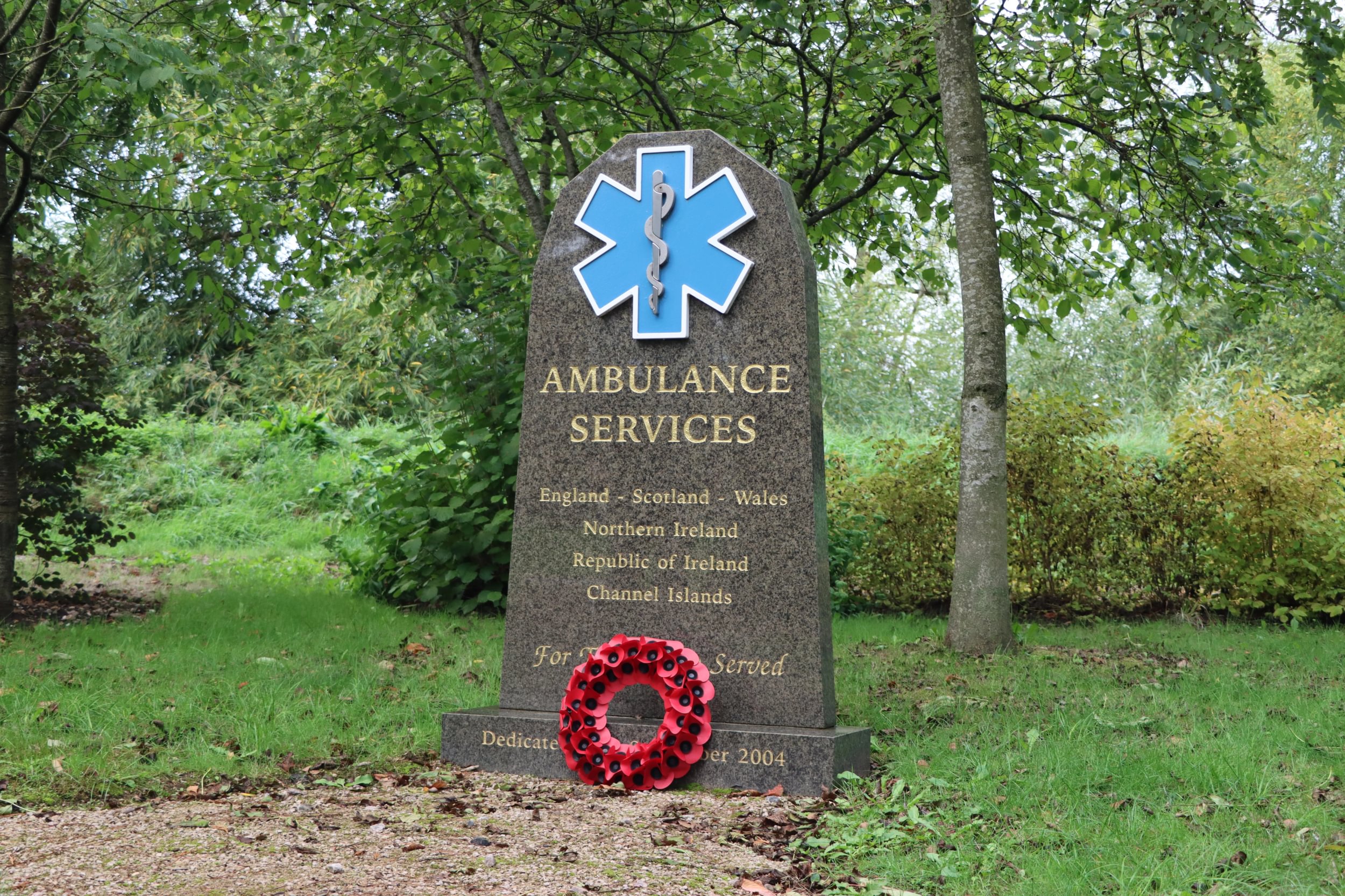A red poppy wreath lays against the Ambulance Services Memorial