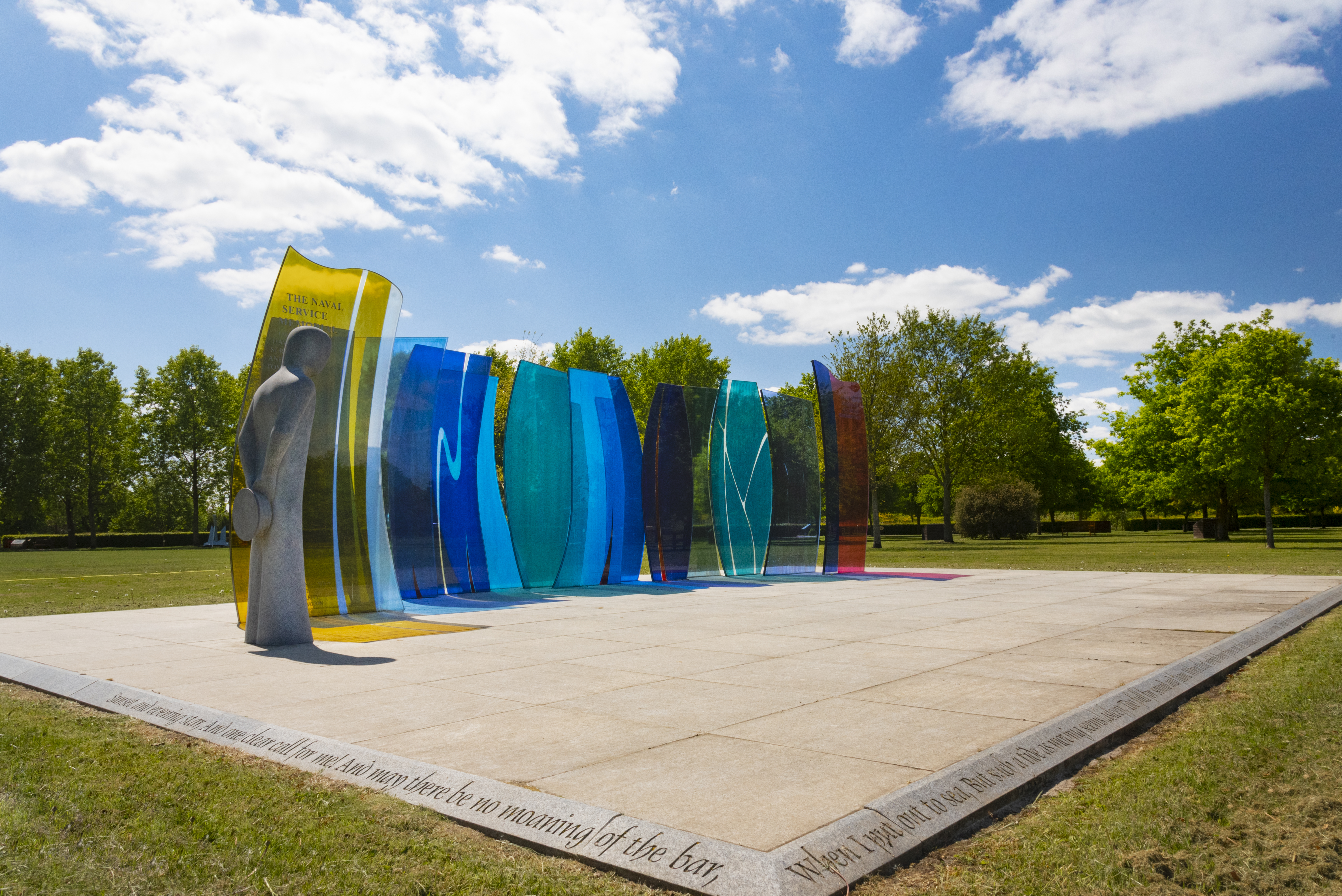 Naval Service Memorial. A lone figure with head down stands before glass panels representing the sun and the oceans