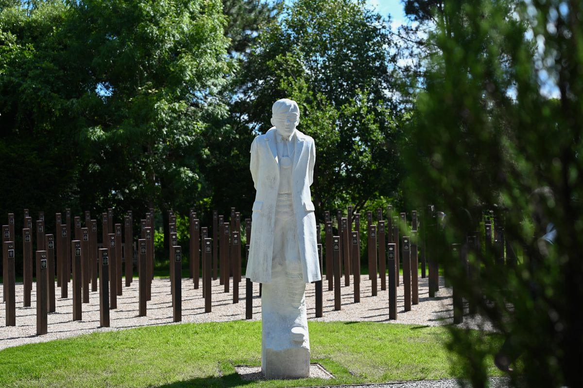 Stone statue of a man with eye covering surrounded by wooden posts