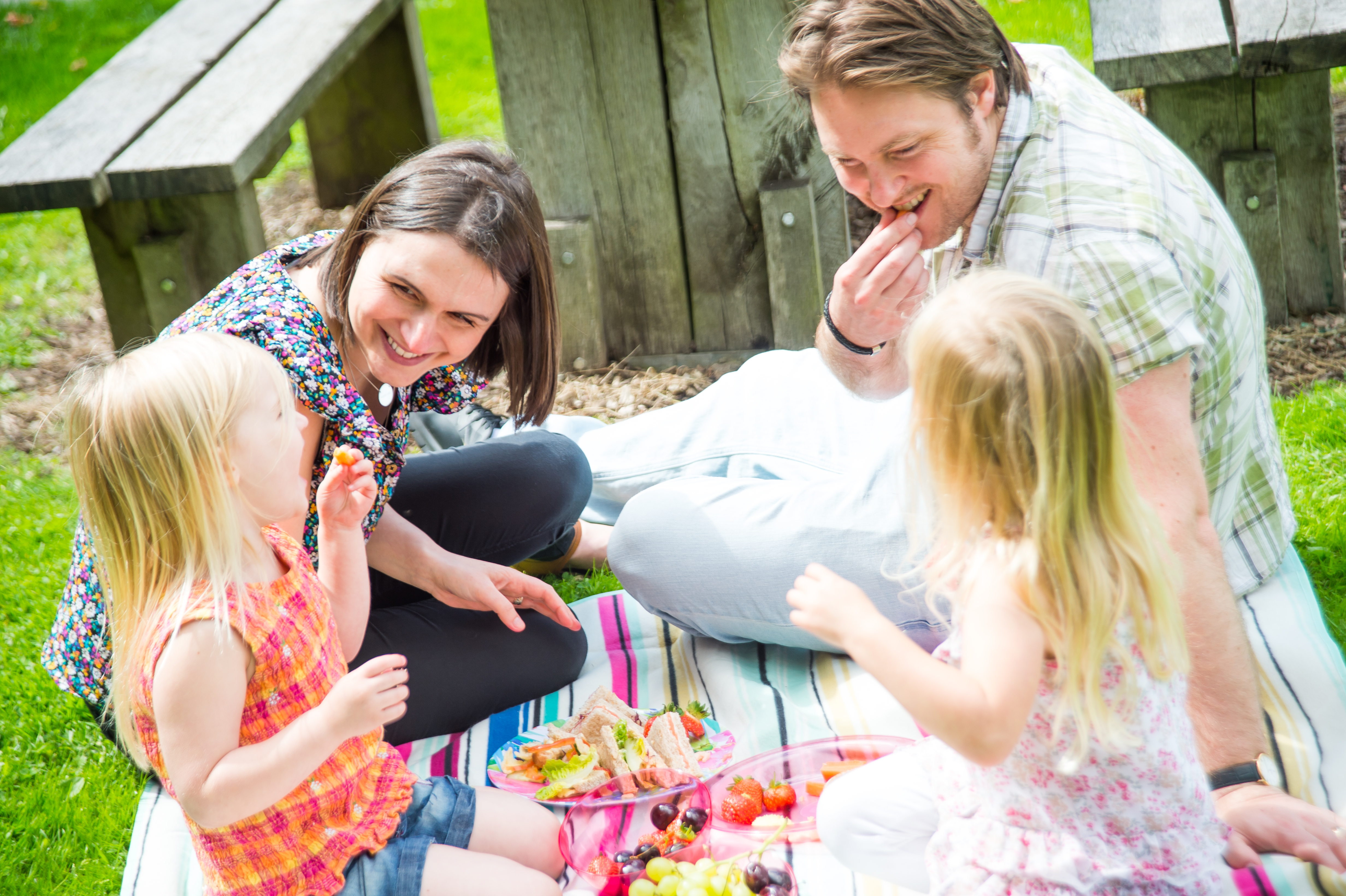 Family having a picnic on the grass. It is sunny and they are smiling.