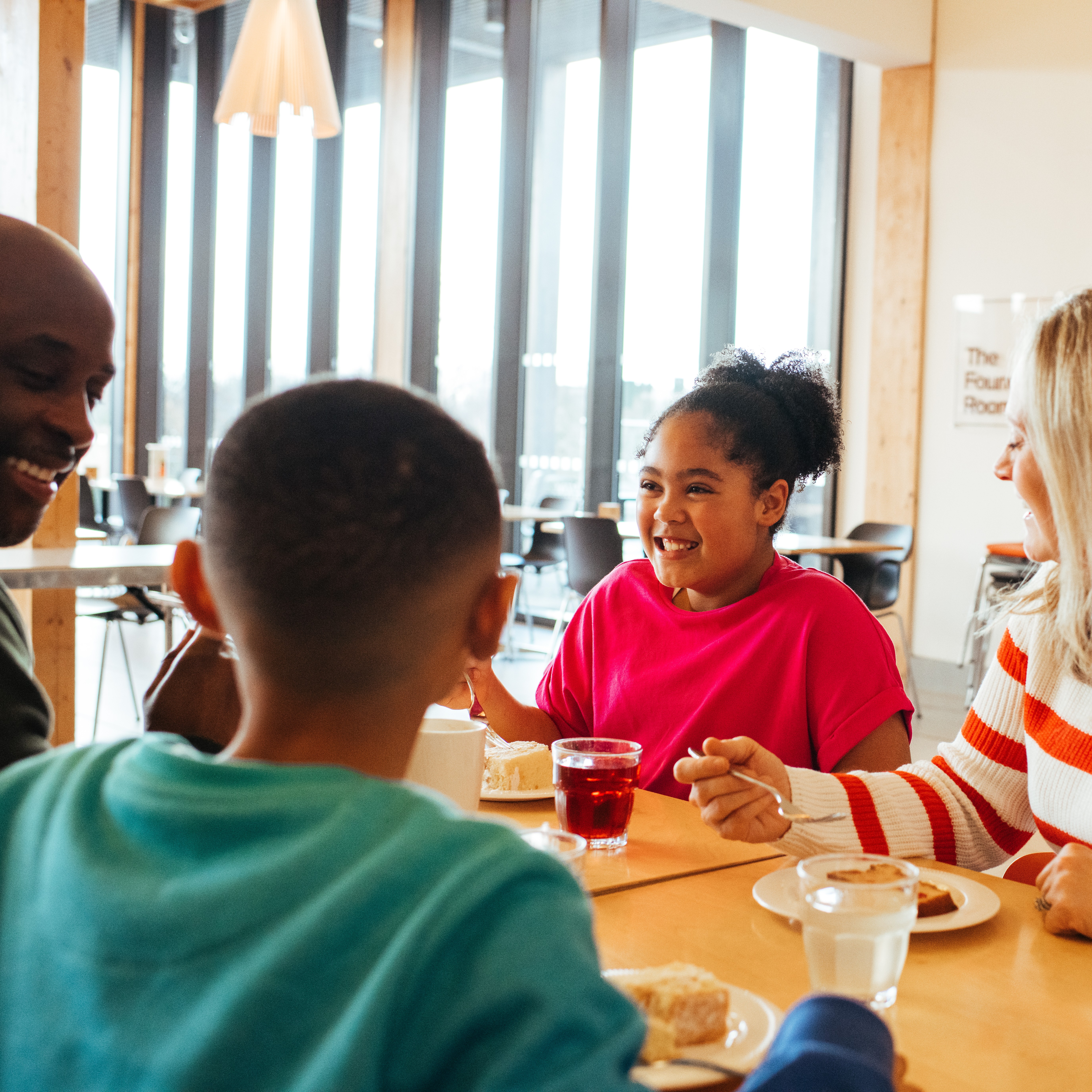 Family dining together in the restaurant, smiling and enjoying a slice of cake.