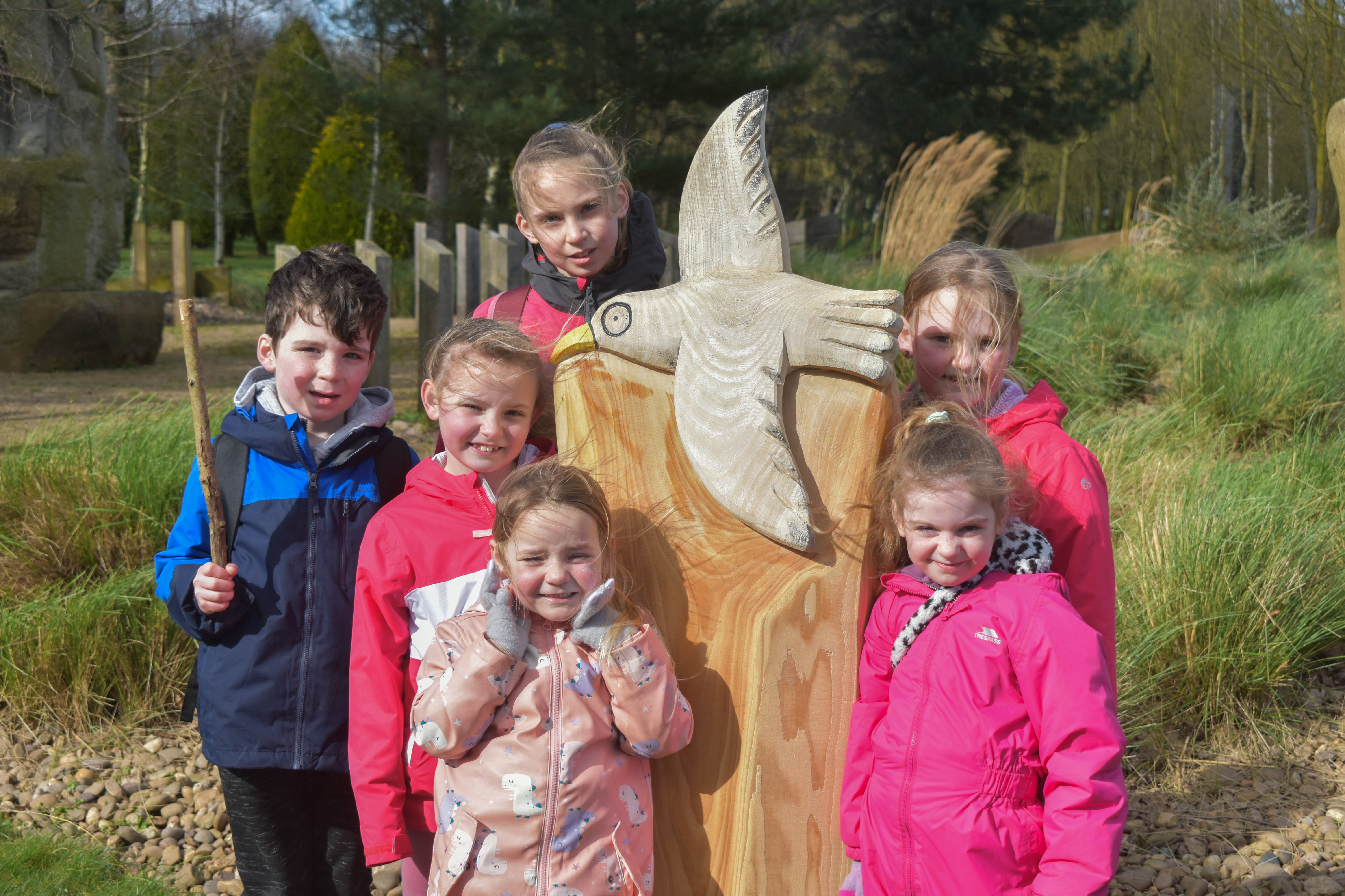 A group of young people stand around the seagull sculpture on the Stick Man Trail.